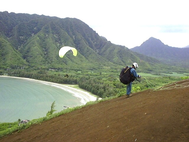 One sails off the hillside while another prepares to launch